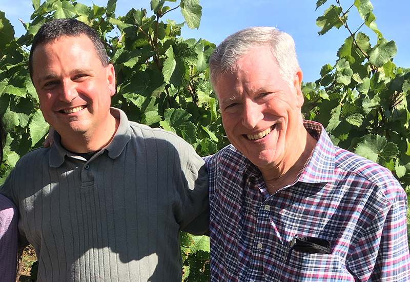 Two men smiling in a vineyard